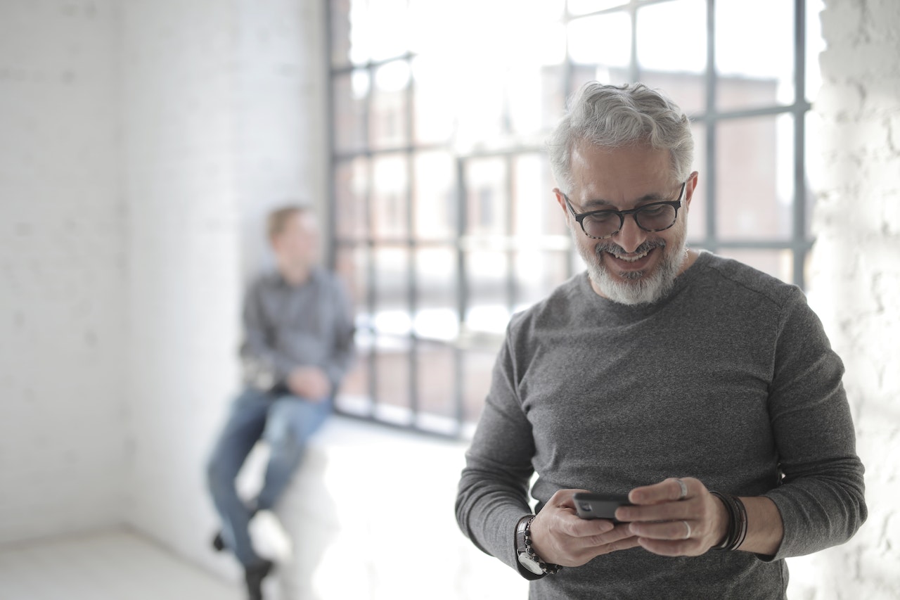 Homme qui sourit face à son téléphone