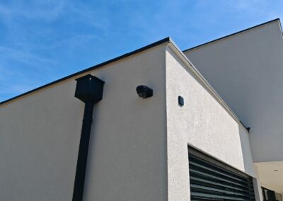 Caméra dôme noire discrètement intégrée à la façade blanche d'une villa moderne