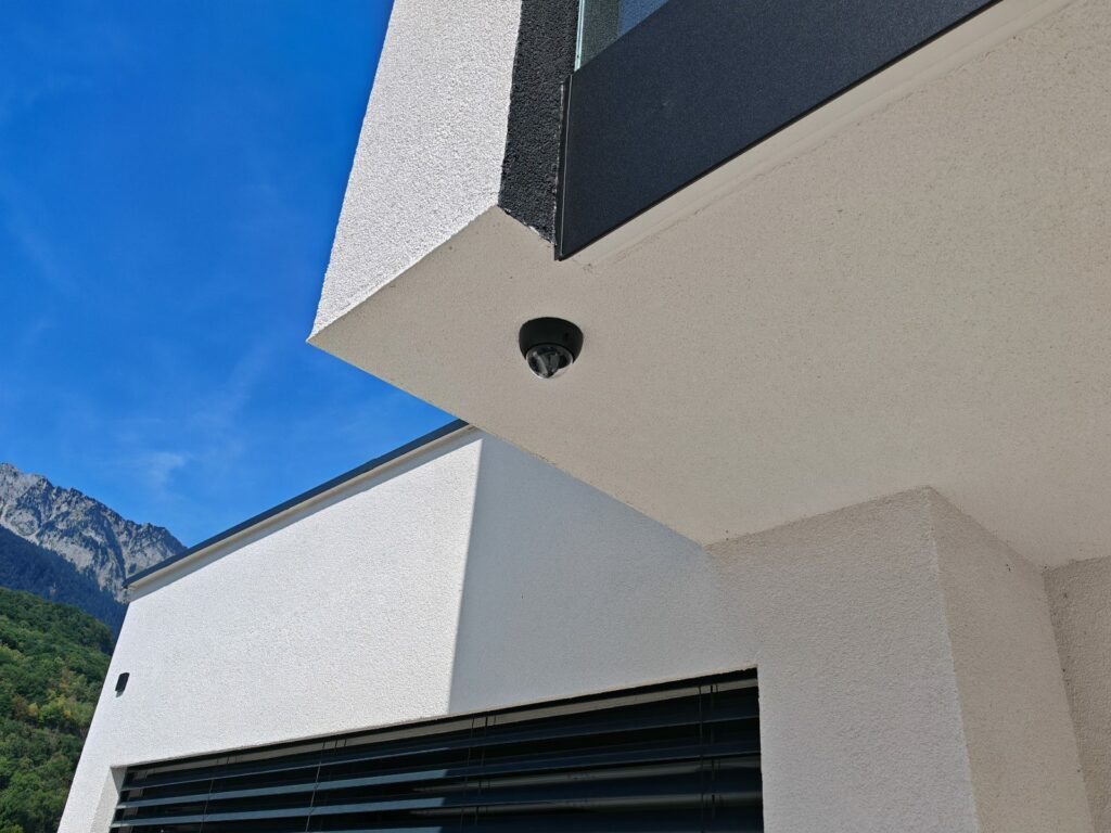 Caméra dôme installée sous l'avant-toit d'une villa contemporaine, avec vue sur les montagnes
