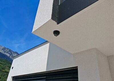 Caméra dôme installée sous l'avant-toit d'une villa contemporaine, avec vue sur les montagnes