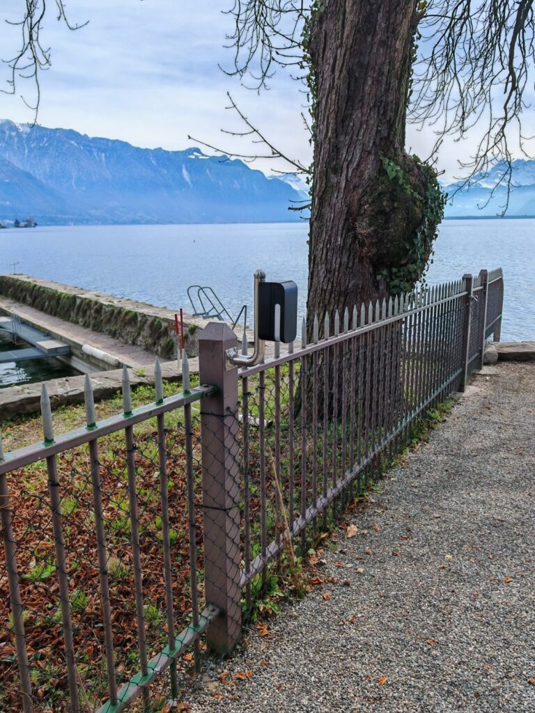 Détecteur extérieur fixé sur la clôture d'une propriété au bord du Léman, face aux Alpes