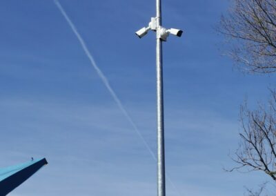 Mât galvanisé équipé de deux caméras de surveillance et d'un éclairage, surveillant les bennes d'une déchetterie