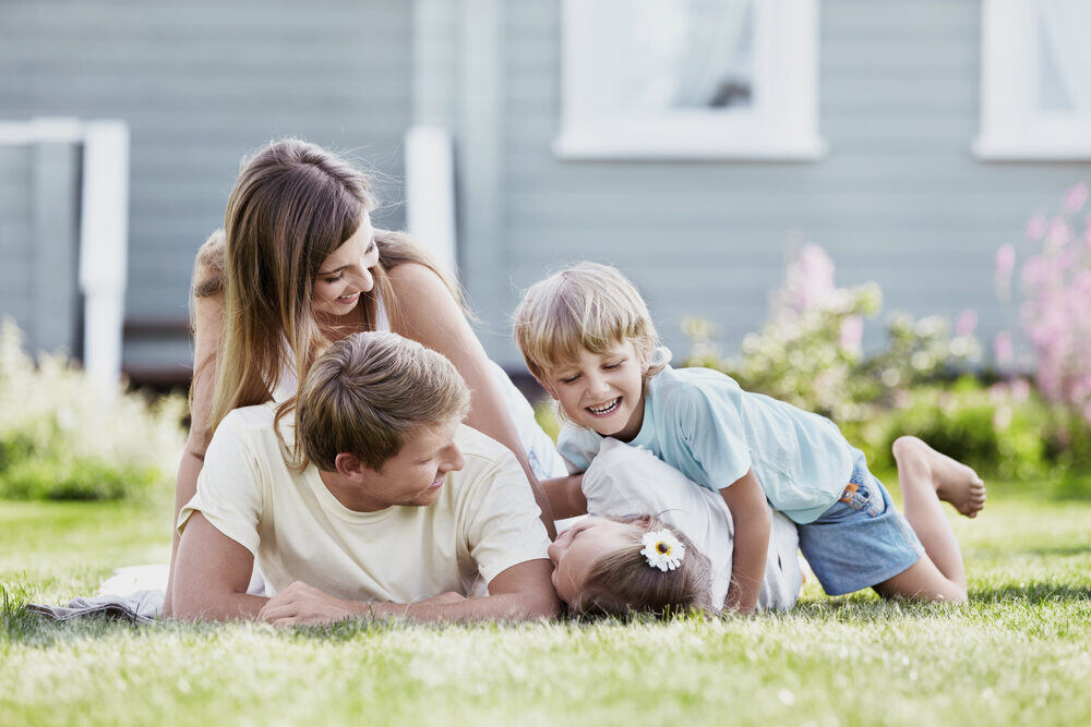 Famille souriante sur la pelouse devant sa maison